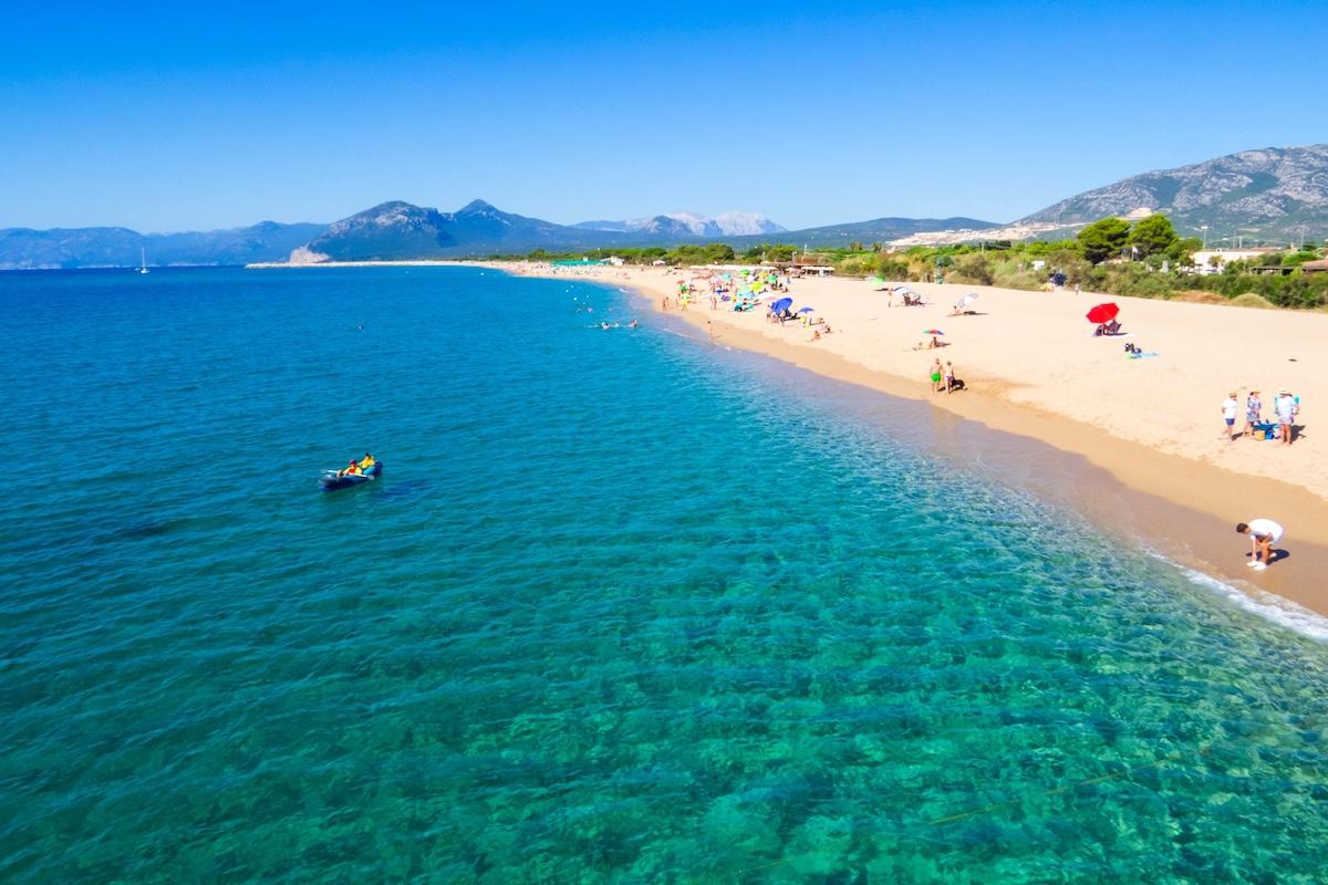 The clear waters and yellow sands at the beach named Spiaggia Marina di Orosei in east Sardinia. In the background, the tall mountains of the Supramonte rise in the distance.